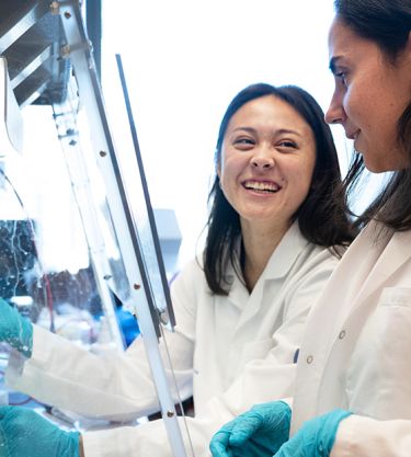 Two scientists in lab coats working and smiling in a laboratory
