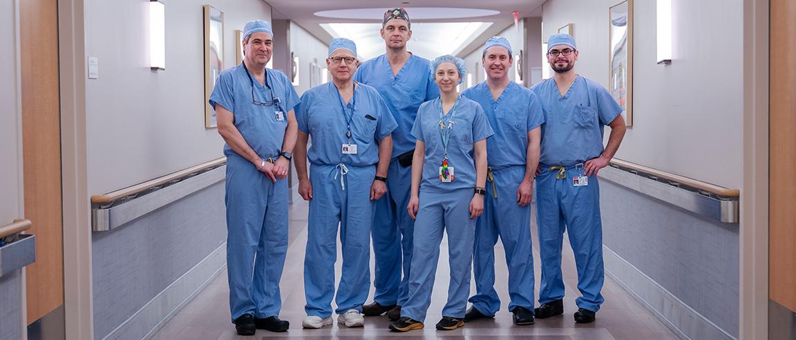 A dark-haired man and two women with long dark hair, all wearing blue MSK hospital scrubs, stand close together and smile thanks to the cancer fundraising donations MSK has received.