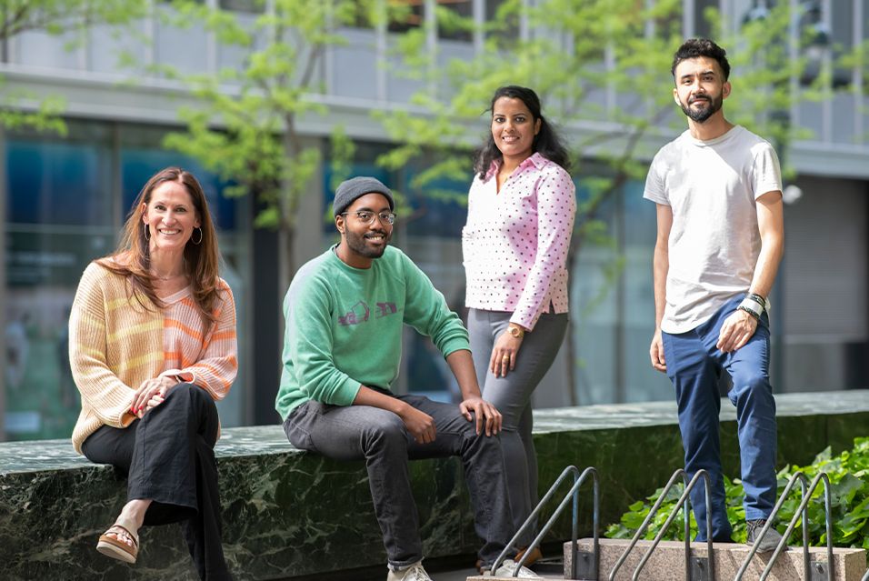 MSK patients Sascha, Avery, Nisha, and Imtiaz, who were all part of the immunotherapy trial, are outside in an urban area.